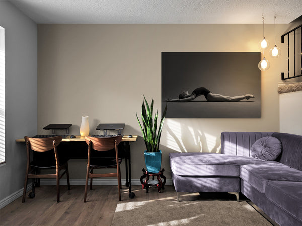 Artwork on the living room wall, giving a chill and meditative vibe. Print image of a ballerina, stretching on the floor, body arch, breathing. Photo print studio, colors black and white